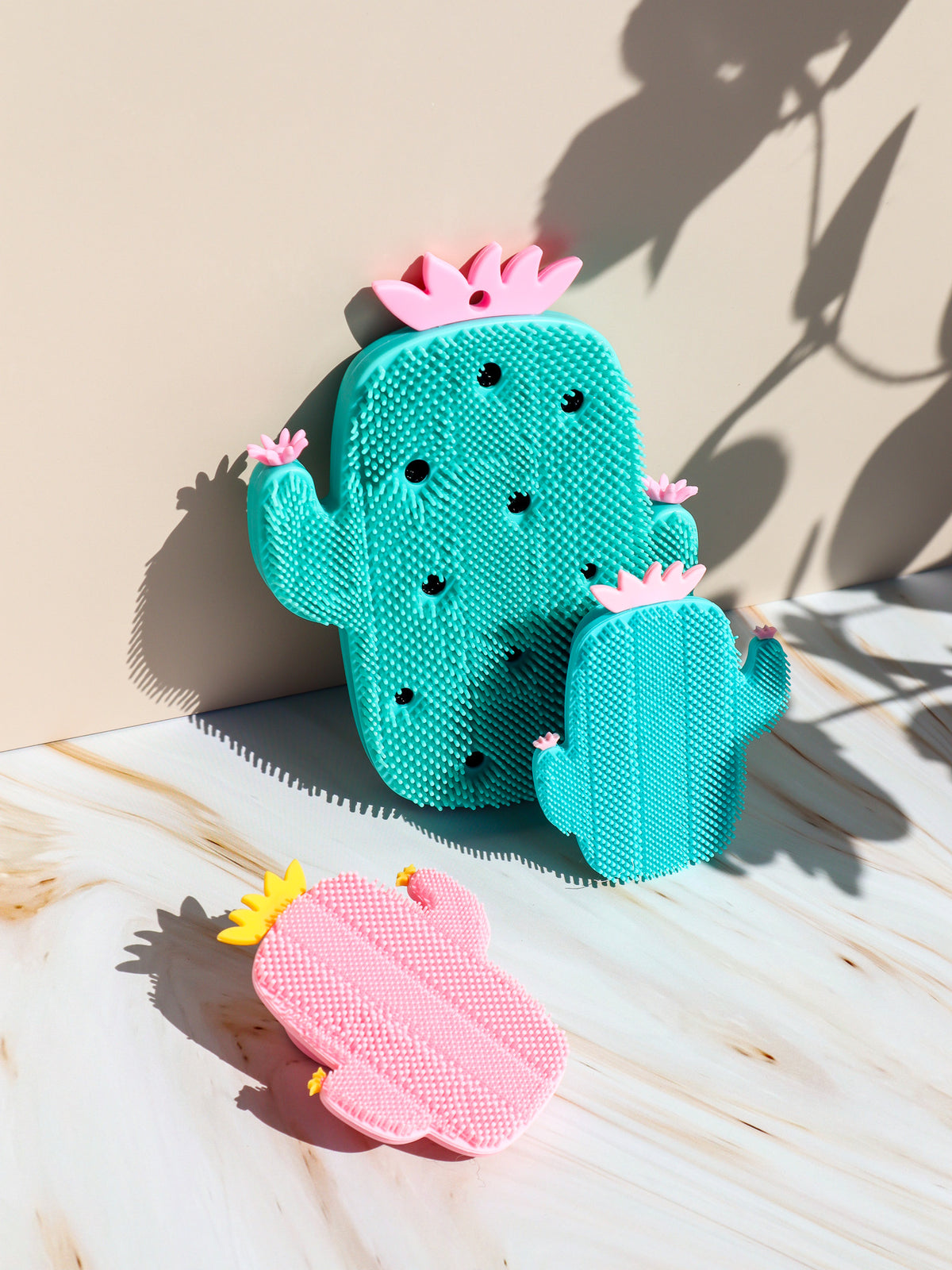 Three Just The Strip Silicone Cactus Bikini and Body Scrubbers in turquoise and pink on white marble