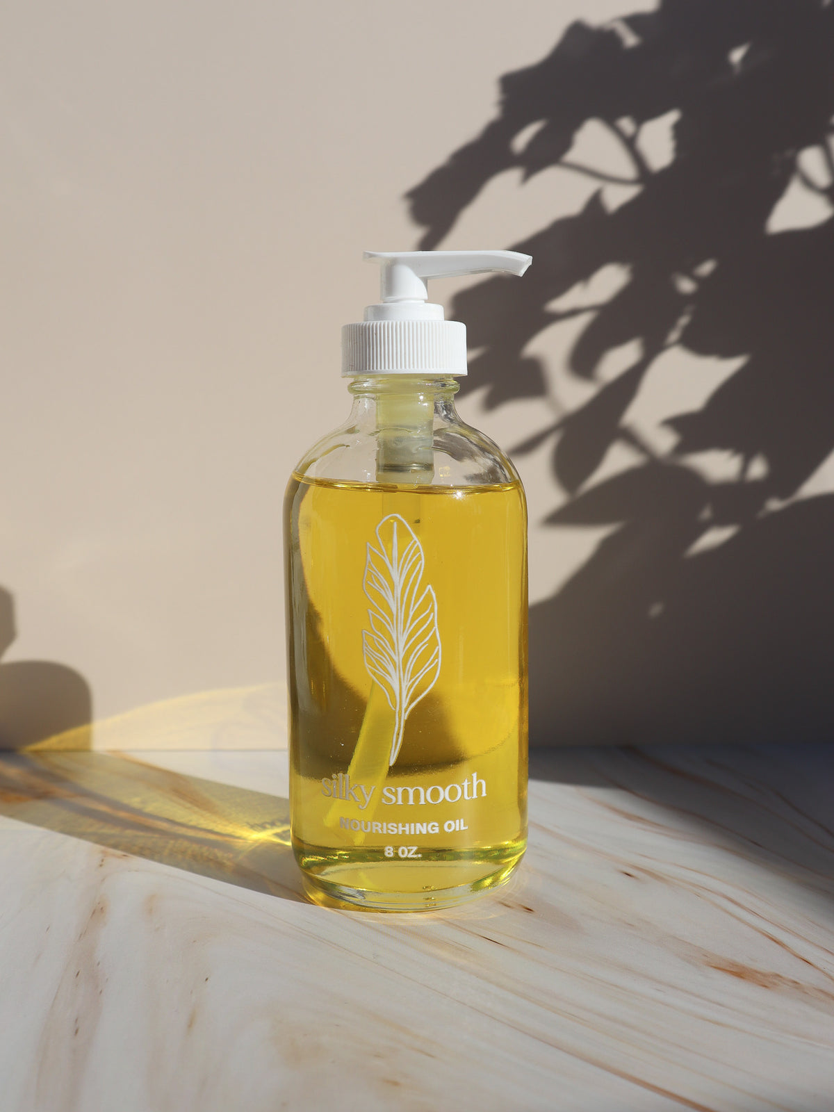 Silky Smooth sandalwood Nourishing Oil in the 8 oz glass pump bottle, the back bar size for waxing studios