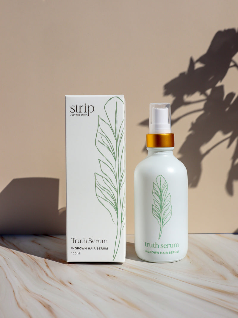 Truth Serum acid free ingrown hair serum in a white glass spray bottle beside its box